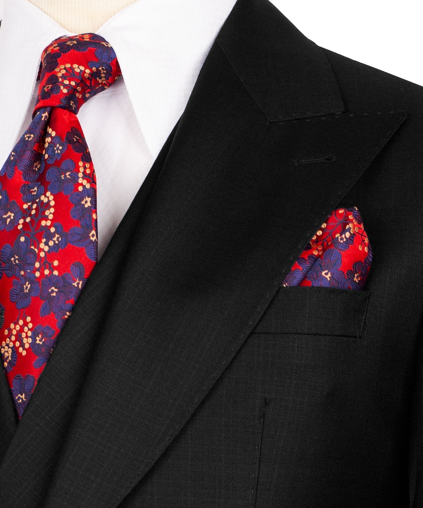Closeup of black lapel with red patterned tie and red pocket square