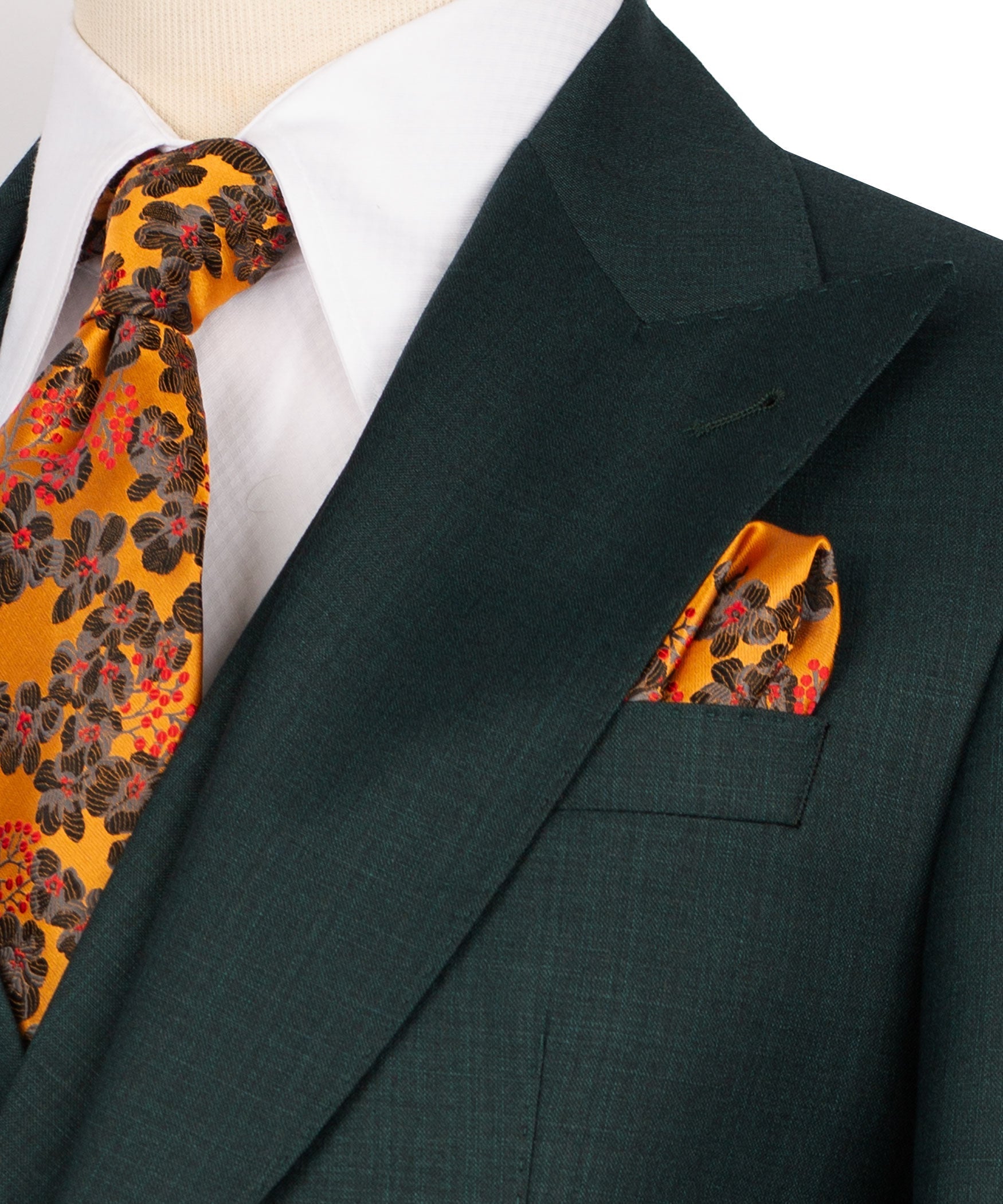 Dark green blazer lapel detail with patterned tie and pocket square