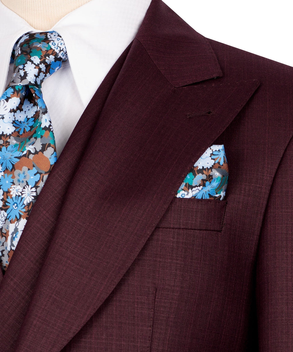 Burgundy suit jacket lapel detail with floral pocket square and tie tip