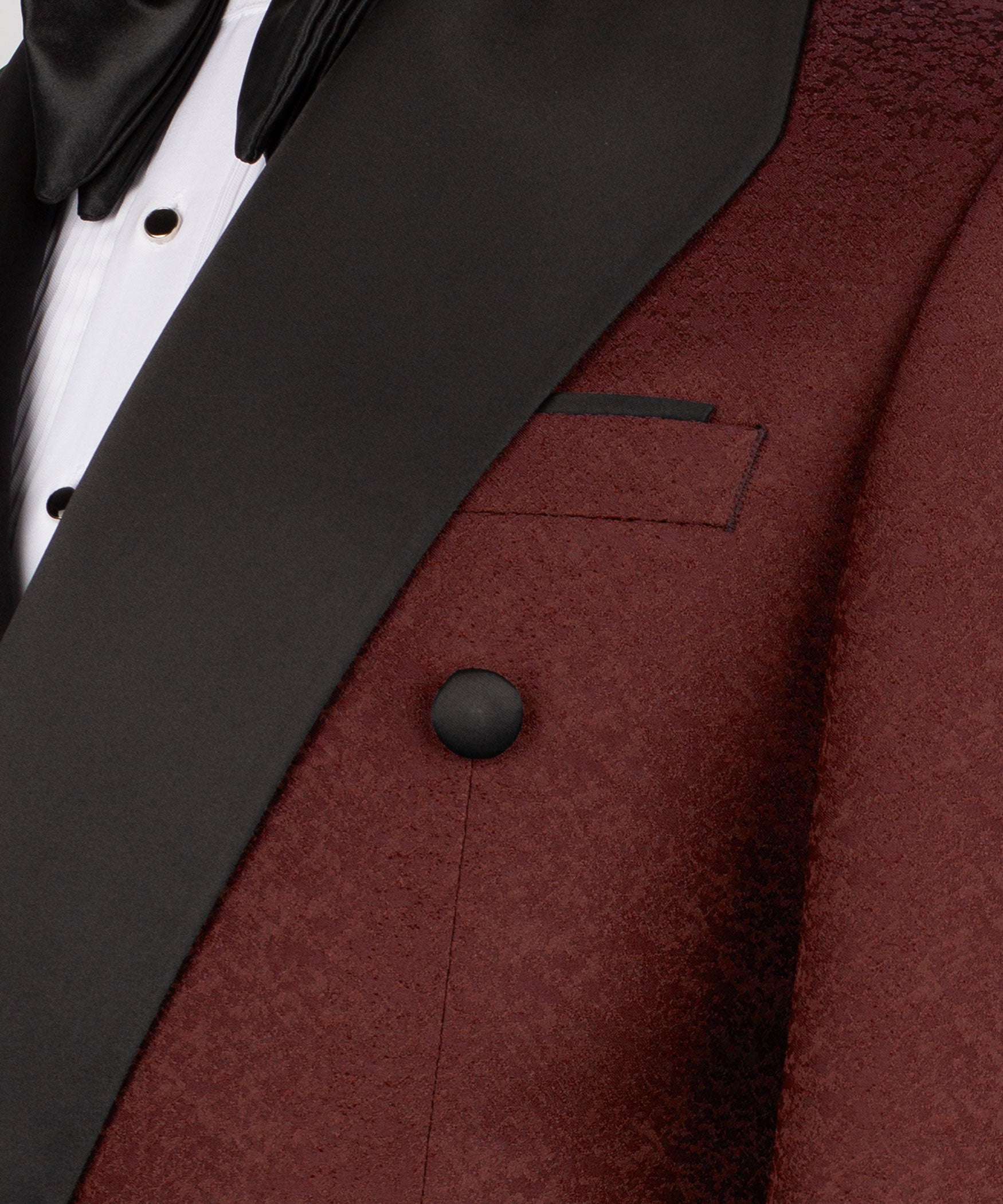 Close-up: black tuxedo lapel, burgundy jacket pocket flap, and button