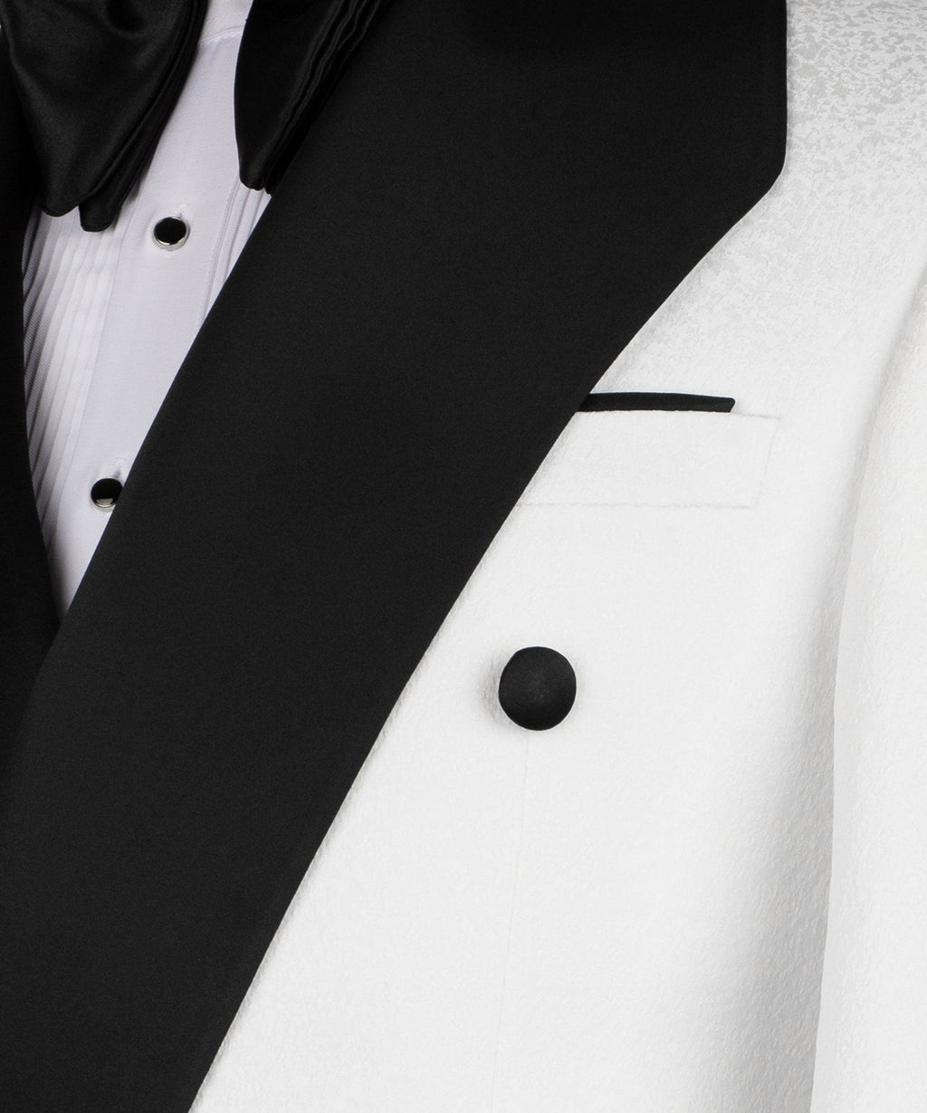 Close-up of black satin lapel and geometric collar detail on white tuxedo jacket