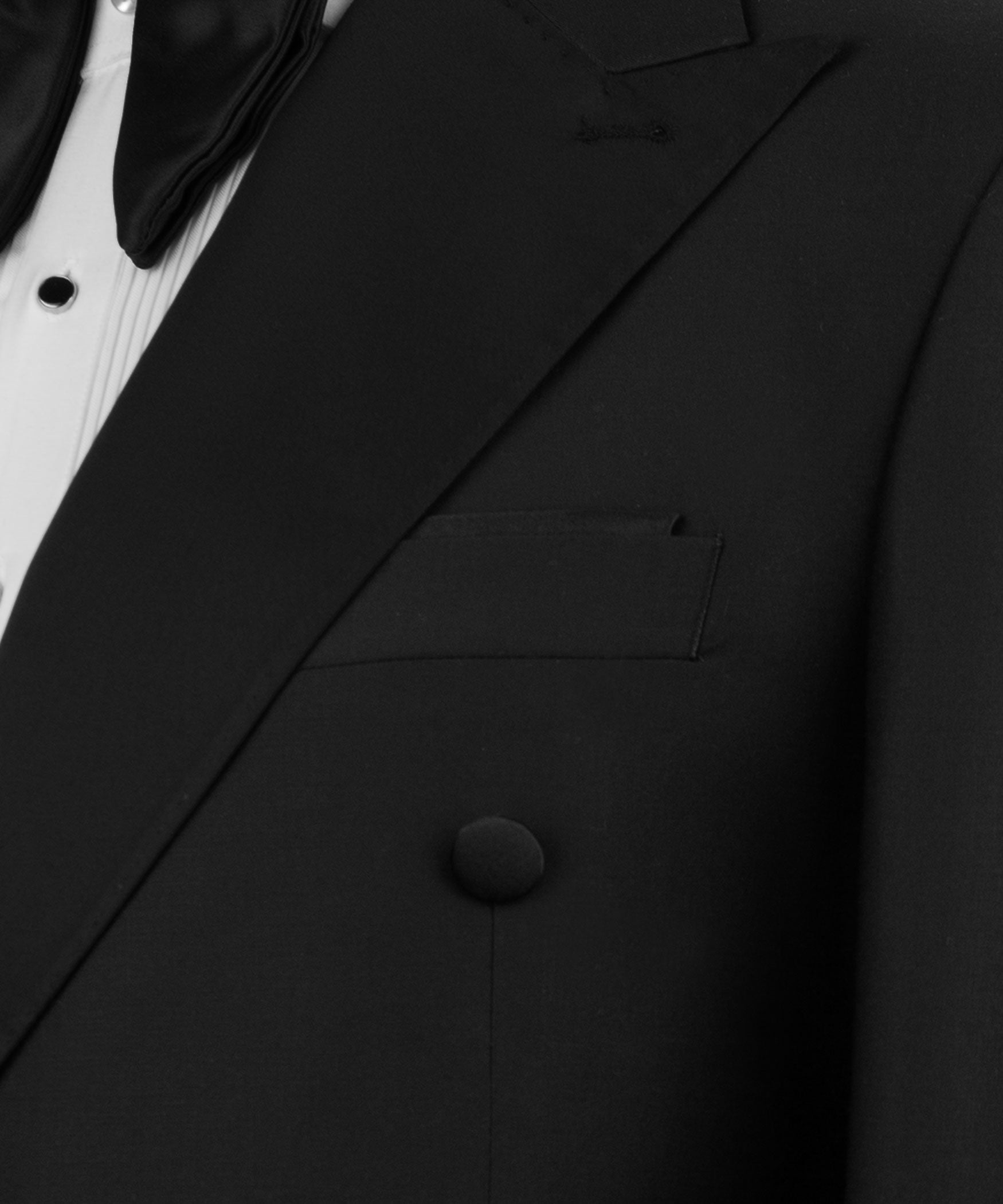 Close-up of black tuxedo jacket lapel with satin trim, pocket flap, and buttons