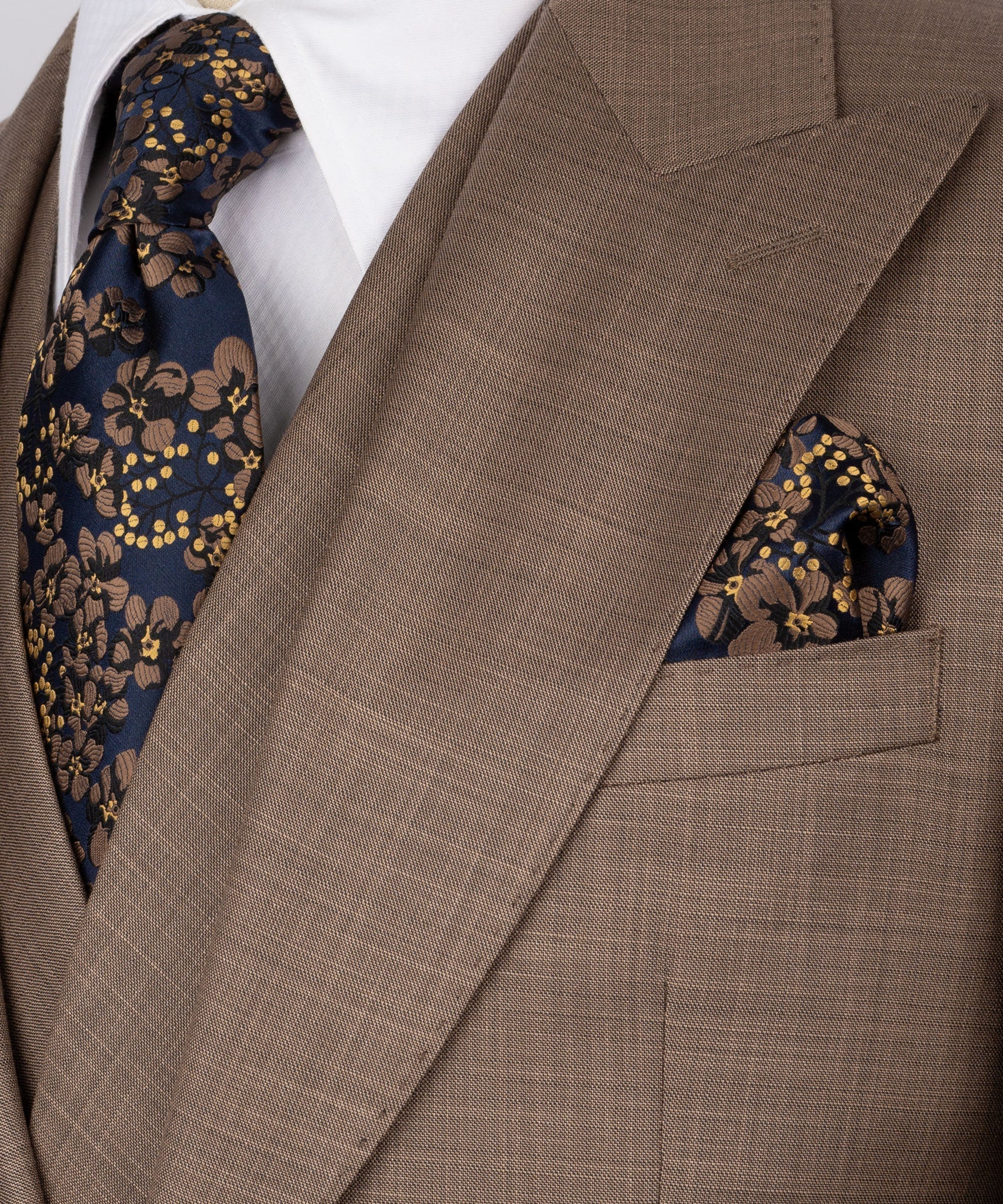 Close-up of taupe blazer lapel with patterned tie and matching pocket square