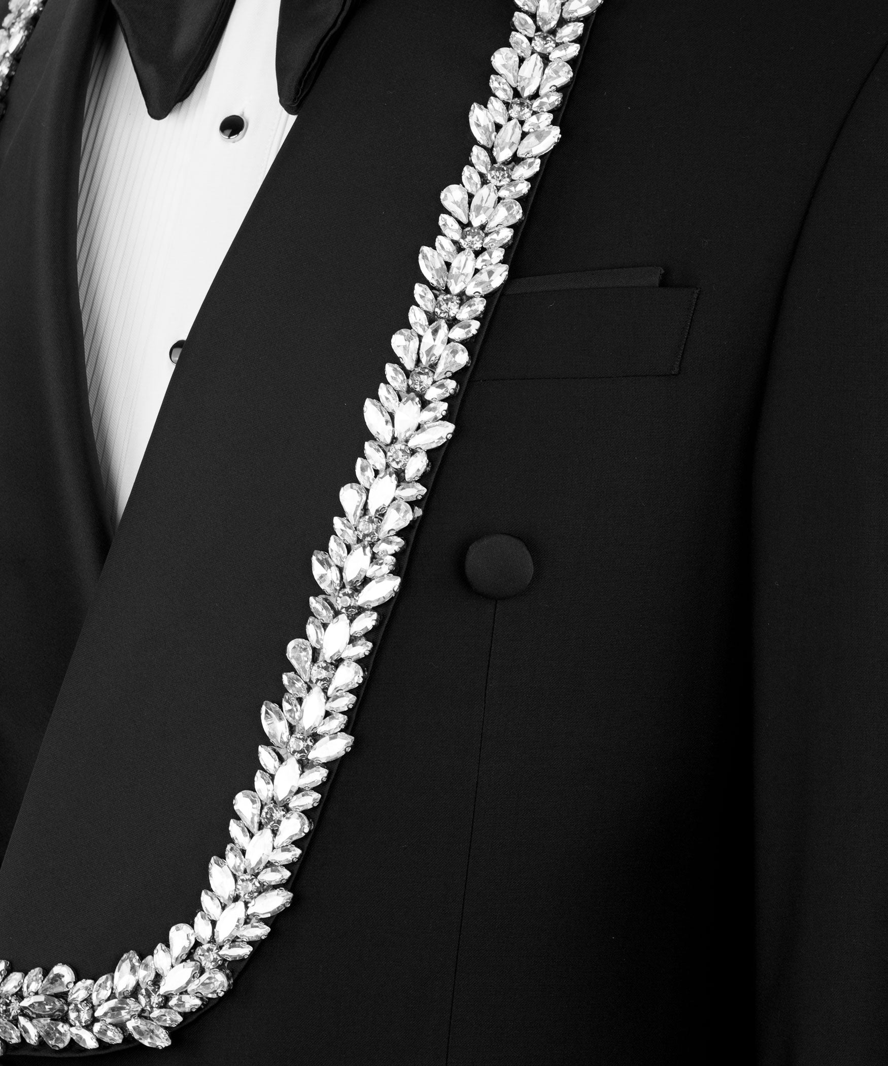 Close-up: white stone-embroidered border on black tuxedo lapel and chest pocket