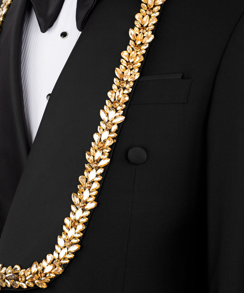 Close-up gold leaf-style chain trim on black tuxedo vest over white shirt