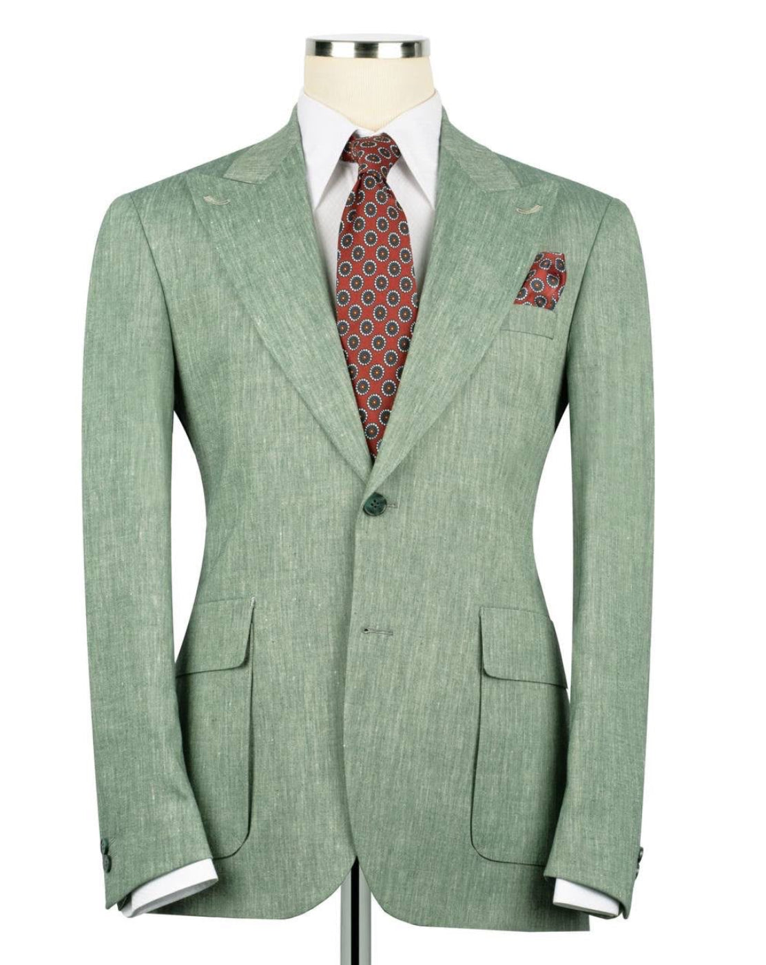 Green suit jacket with a red patterned tie and pocket square on a mannequin against a white background