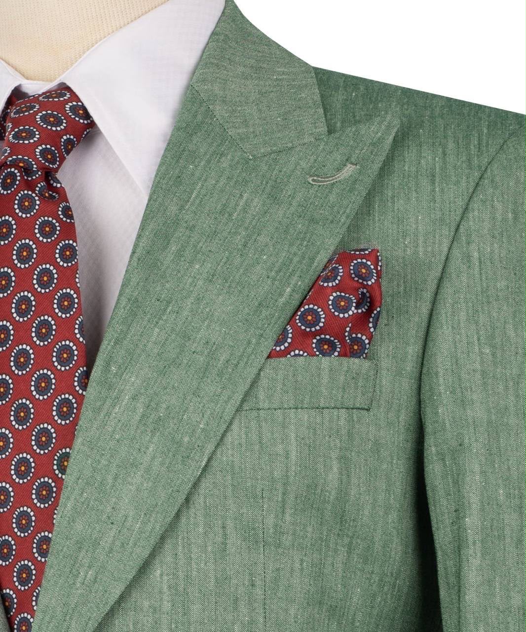 Green suit jacket with red patterned tie and pocket square on a mannequin.