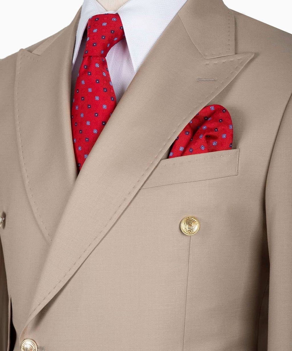 A close-up of a beige double-breasted suit jacket styled with a white dress shirt, a red patterned necktie, and a matching red pocket square.