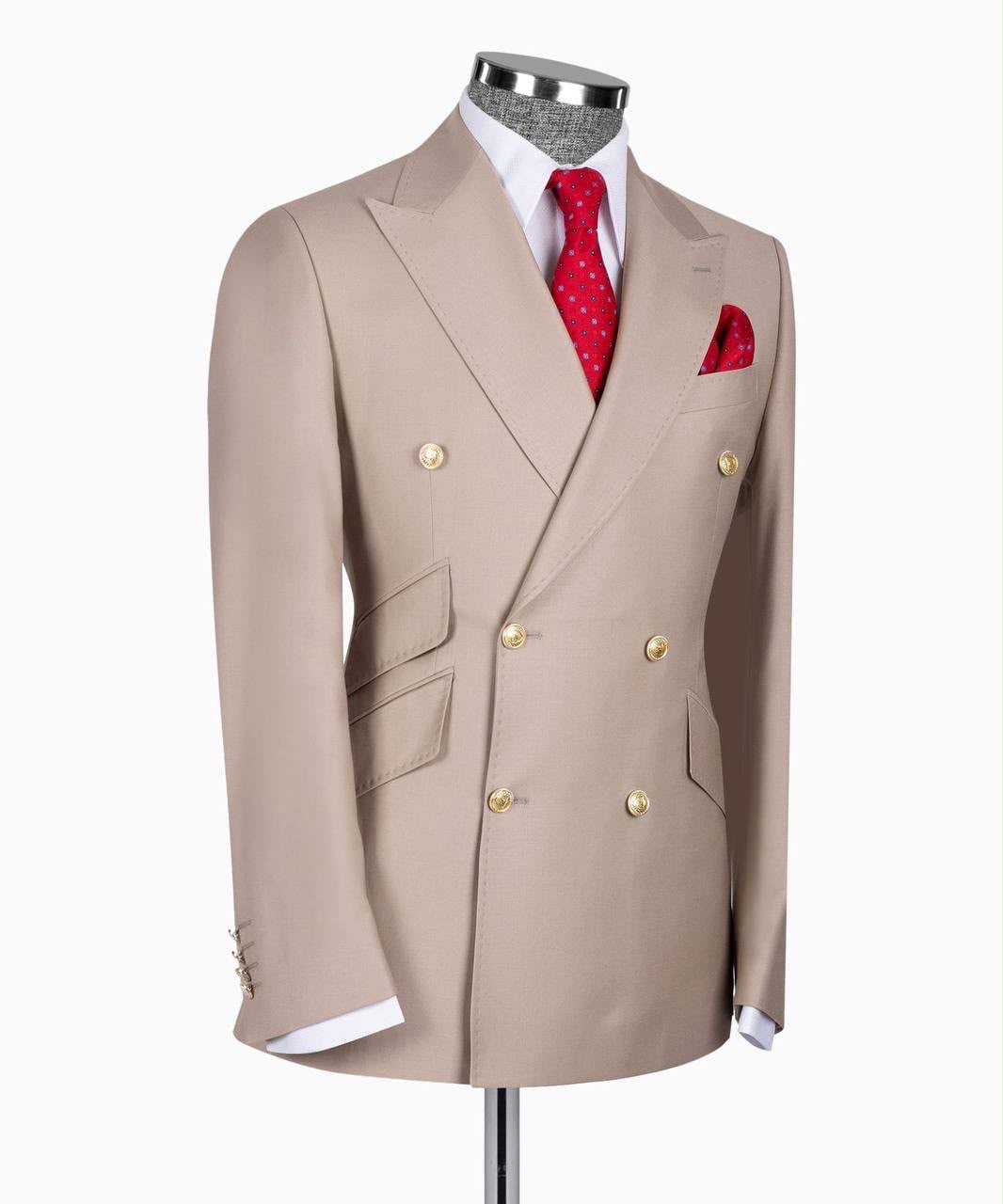 A beige double-breasted suit jacket displayed on a mannequin torso, styled with a white dress shirt, a red patterned tie, and a matching red pocket square 