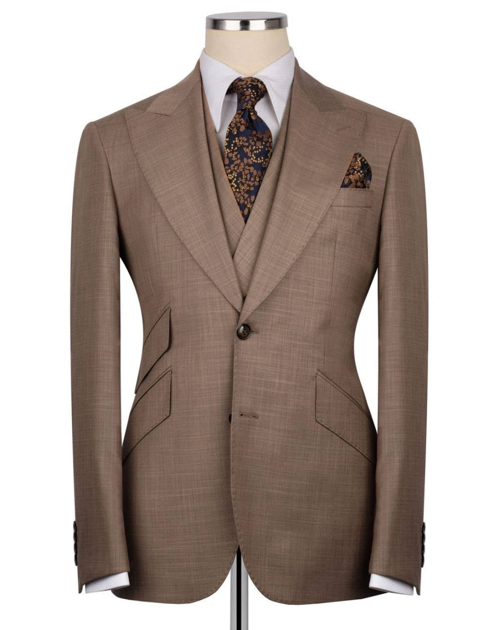 A brown single-breasted suit jacket displayed on a mannequin torso, styled with a white dress shirt, a patterned brown and gold tie, and a matching pocket square.