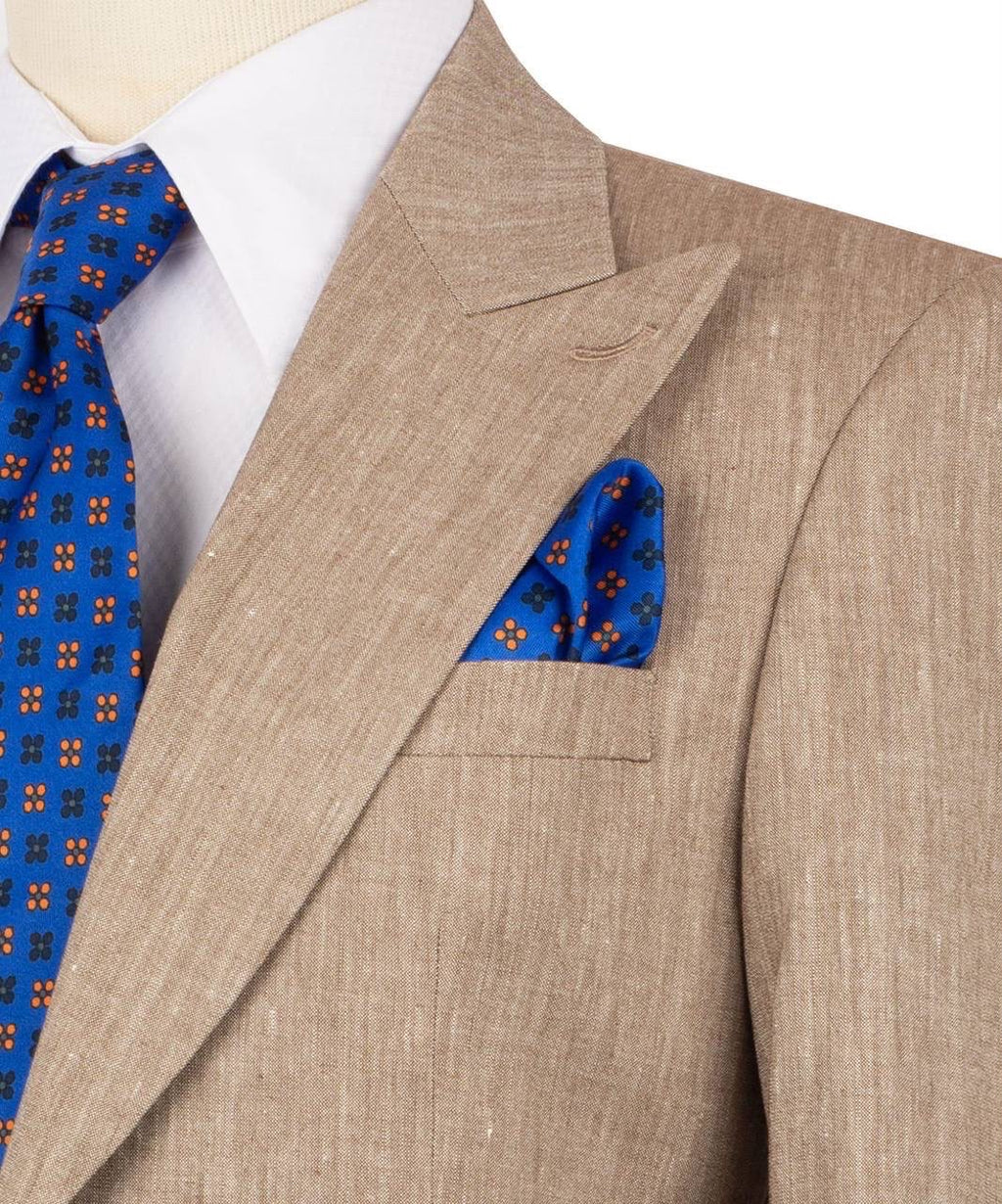 Beige suit jacket with blue patterned tie and pocket square on a mannequin.