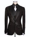 A black tuxedo jacket with ornate beaded and embroidered detailing on the shoulders and chest, styled on a mannequin with a black satin bow tie and white shirt.