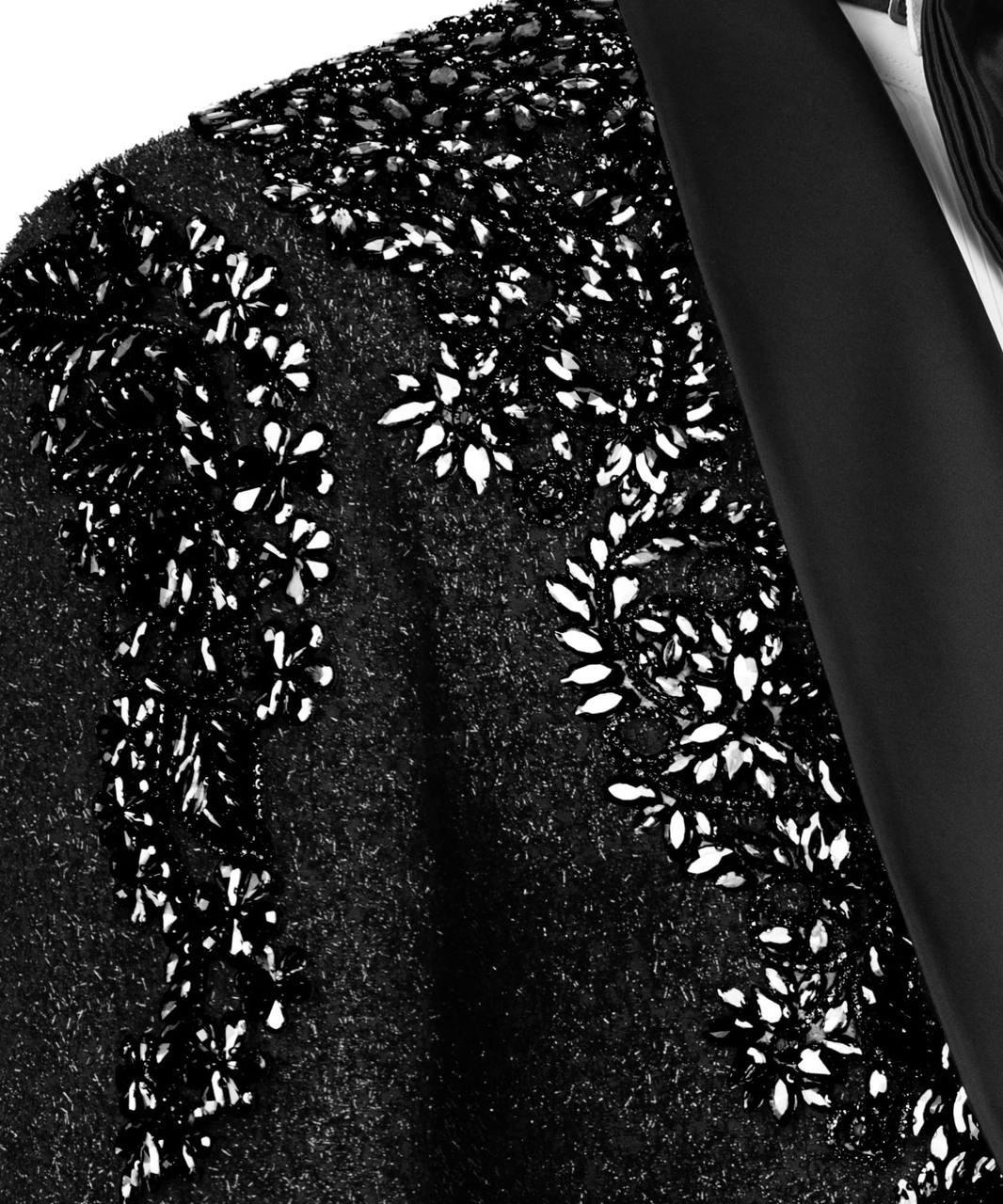 Close-up of a black fabric with white floral embroidery on a white background