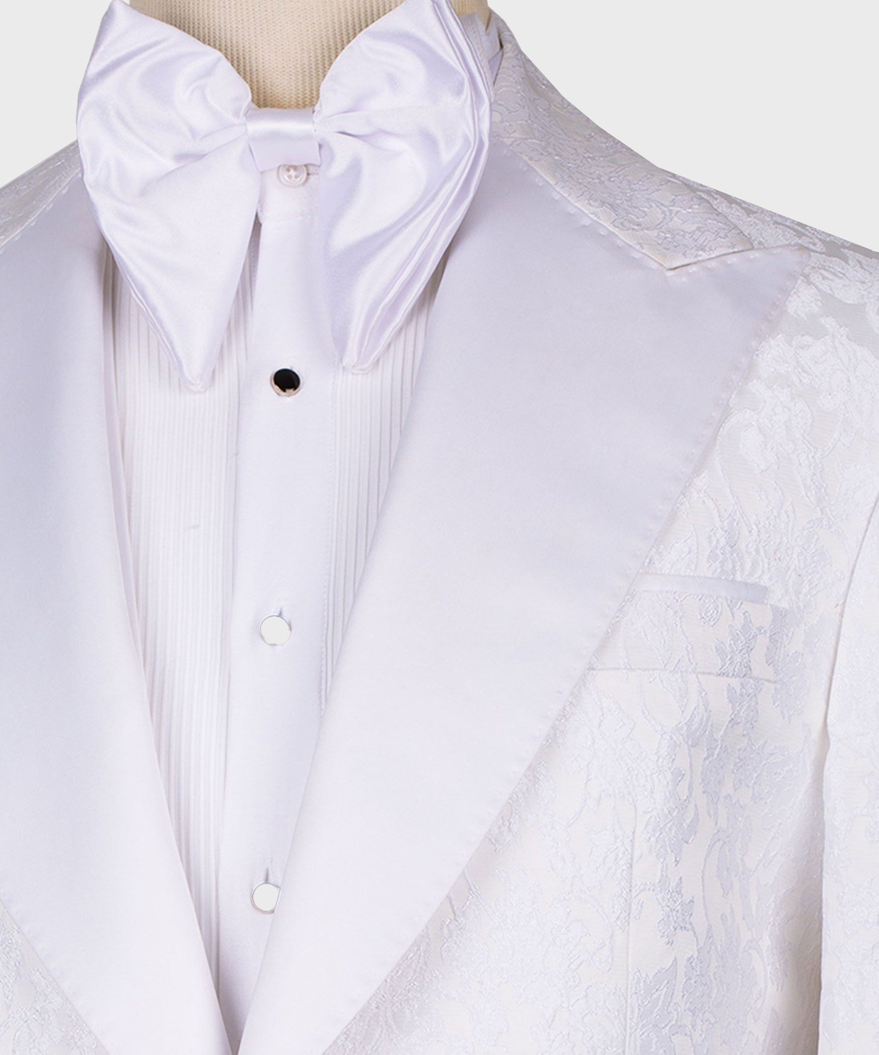 Close-up of white pointed-collar tuxedo with bow tie and black buttons; patterned lapel