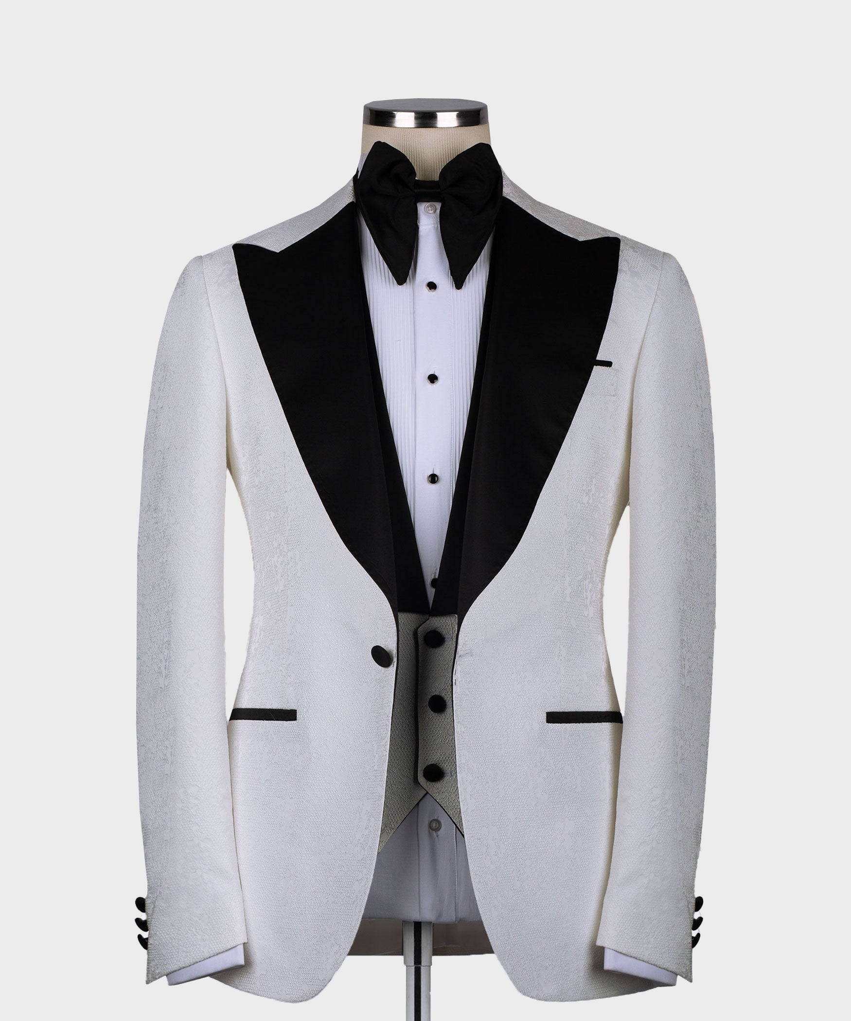 White tuxedo jacket with black satin lapels, pointed collar, and bow tie