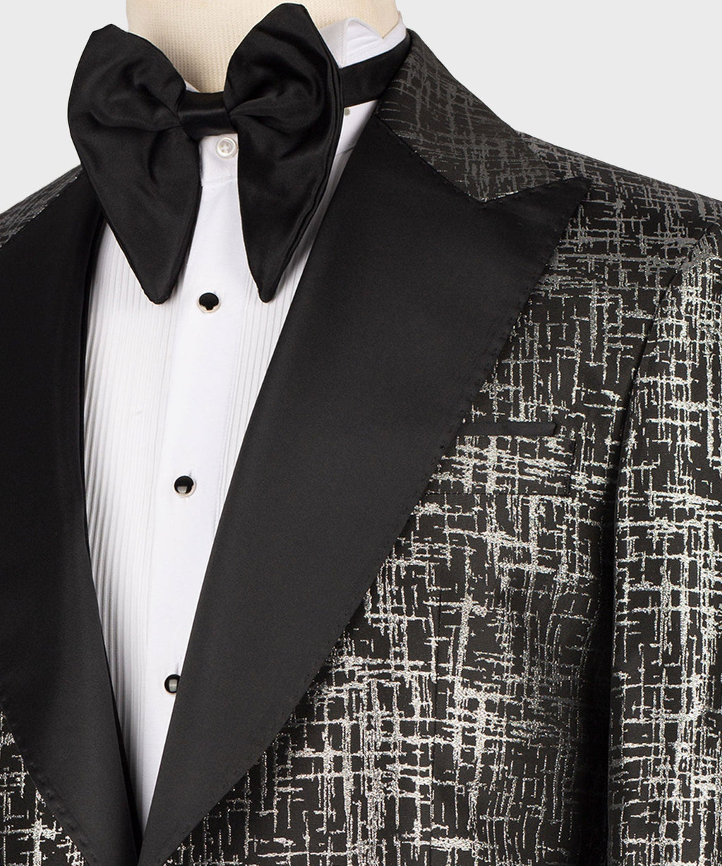 Close-up of black bow tie and pointed satin lapel on textured tuxedo jacket