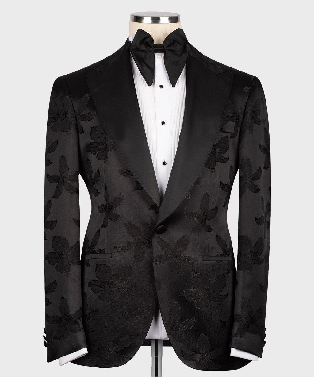 Black tuxedo jacket with pointed lapels over buttoned vest and bow tie