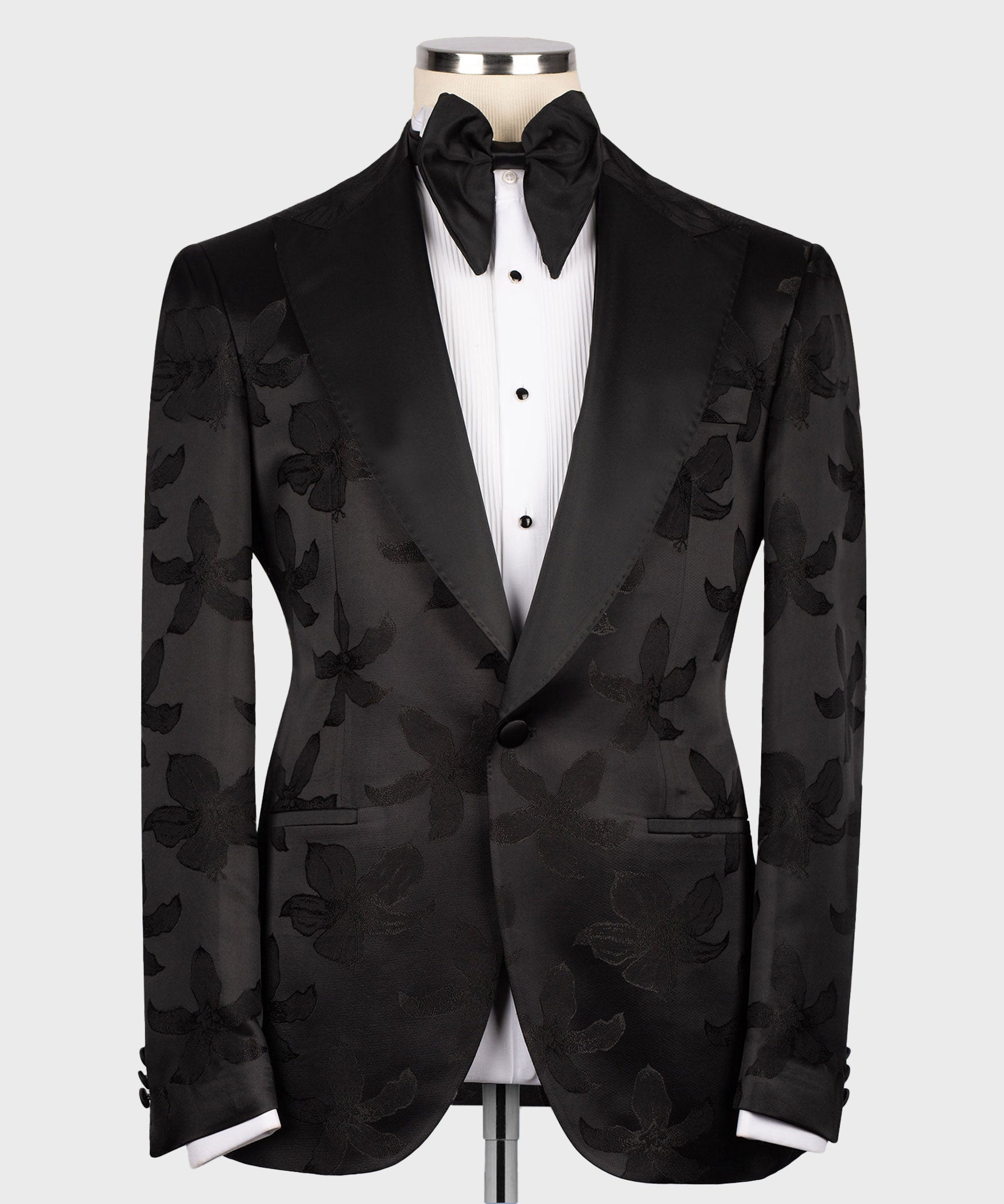 Black tuxedo jacket with pointed lapels over buttoned vest and bow tie