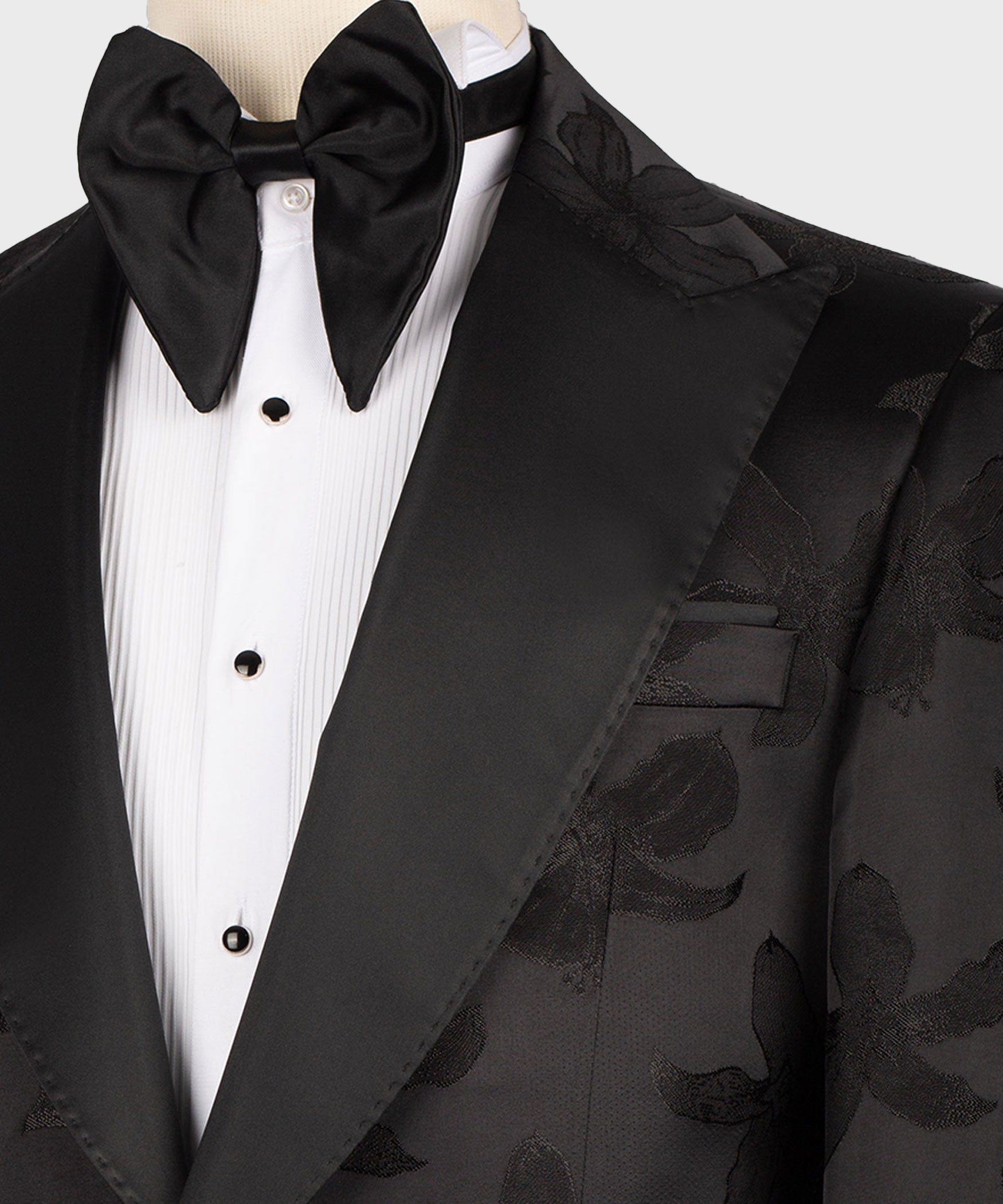 Close-up of black bow tie, white dress shirt placket, and satin tuxedo lapel