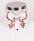 Close-up of a luxury men's white satin bow tie embellished with red crystals, styled on a Koss Atelier pleated tuxedo shirt with black studs.